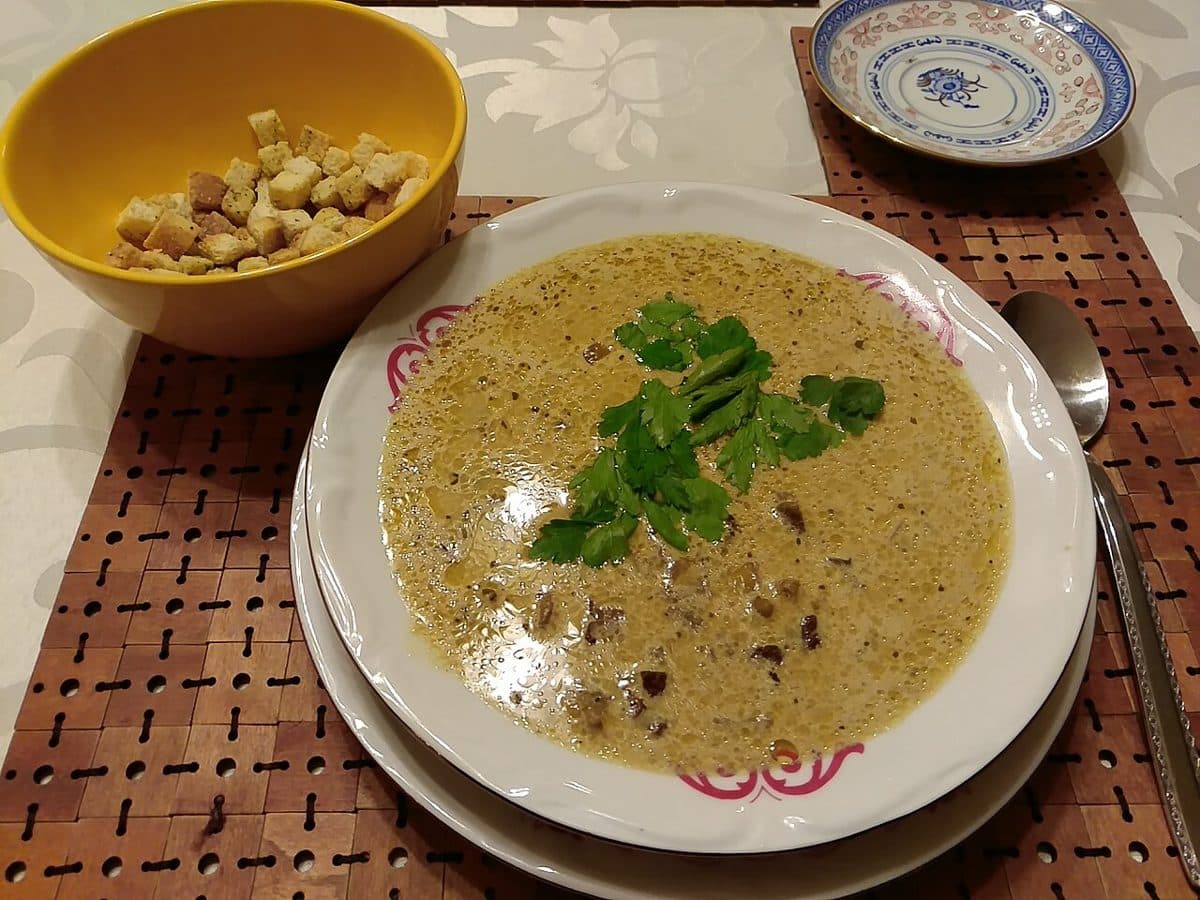 Kremowa zupa grzybowa ze śmietaną i natką pietruszki w talerzu