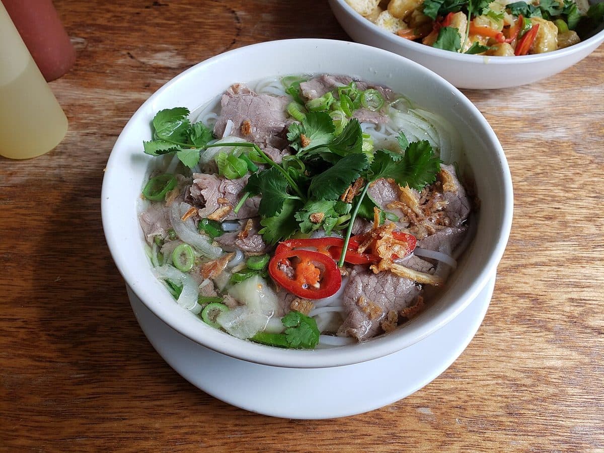 Miska wietnamskiej zupy pho z wołowiną, makaronem ryżowym, chili i ziołami